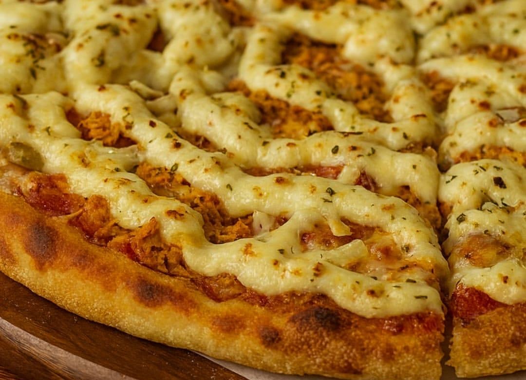 Pizza de frango com Catupiry RoFit, queijo gratinado e borda dourada sobre uma tábua